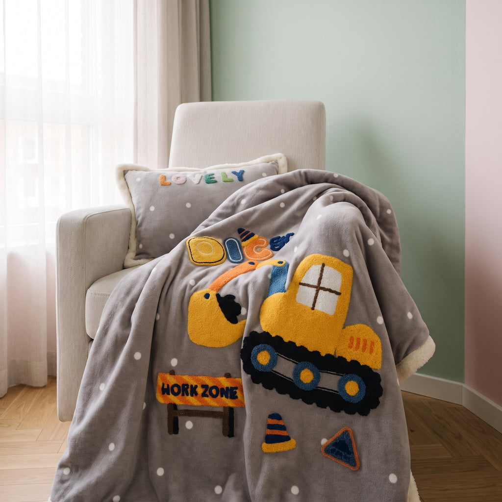 Couverture bébé grise et coussin assorti dans un fauteuil d’enfant