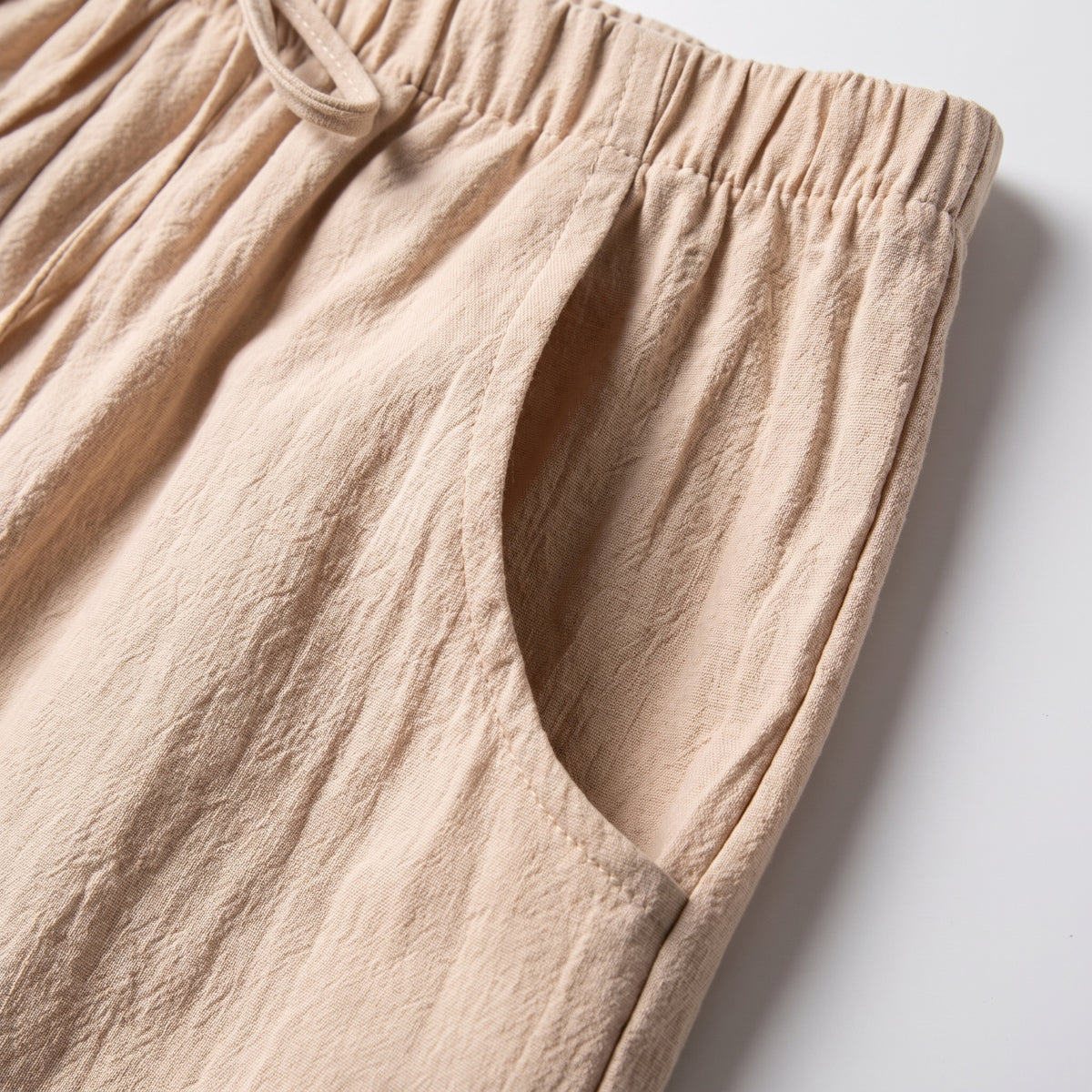 Gros plan sur une poche latérale et la ceinture froncée d'un short en coton et lin beige