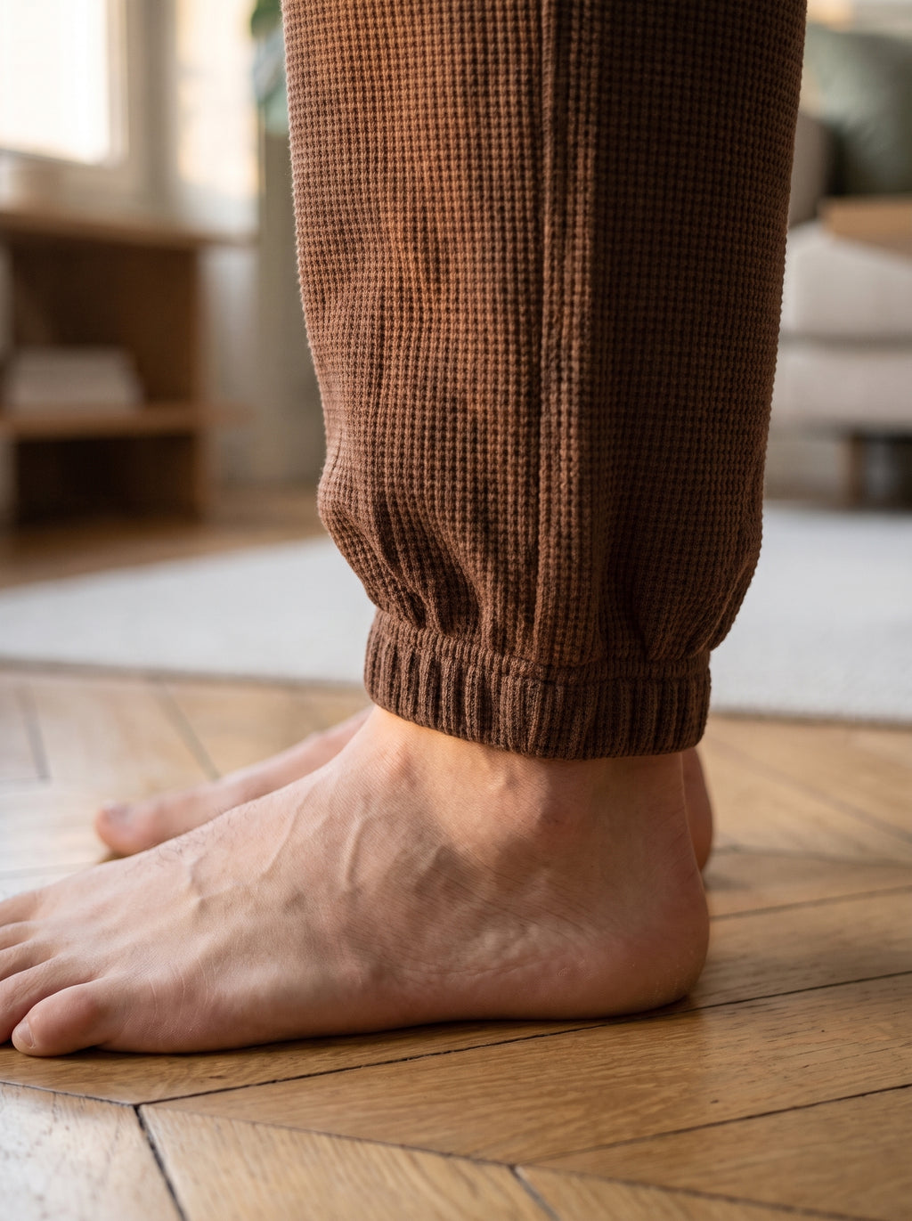 Gros plan sur le bord-cote elastique du bas de jambe, pied nu sur le parquet