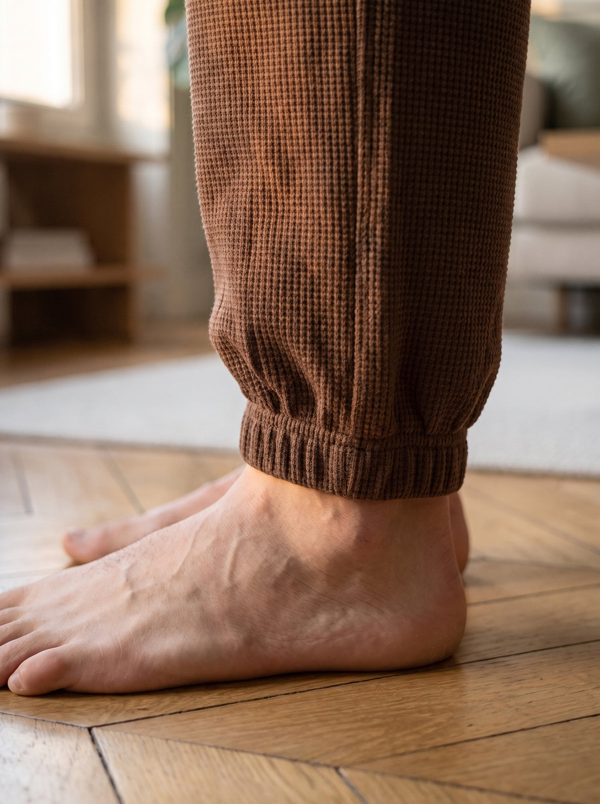 Gros plan sur le bord-cote elastique du bas de jambe, pied nu sur le parquet