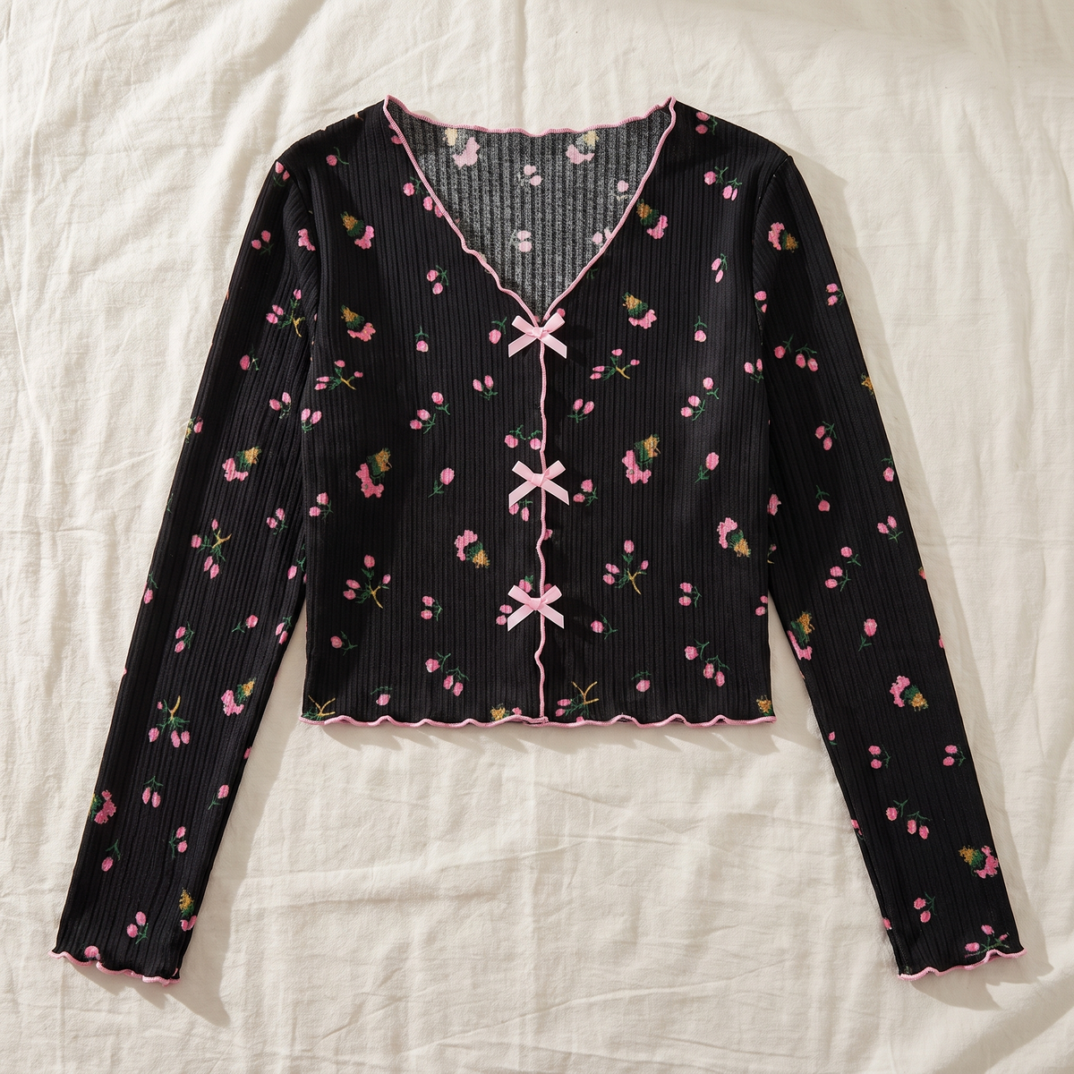 Vue rapprochée des trois liens noués du haut du pyjama floral noir.