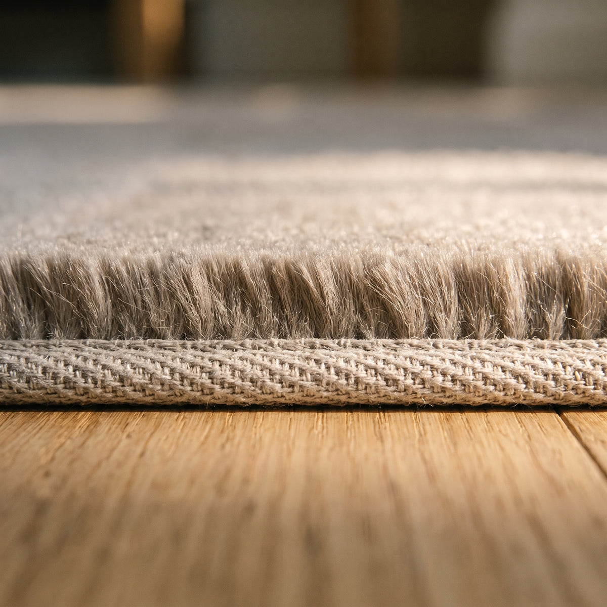 Bord du tapis en fausse fourrure beige posé sur un parquet clair, poil ras et envers tissé visibles