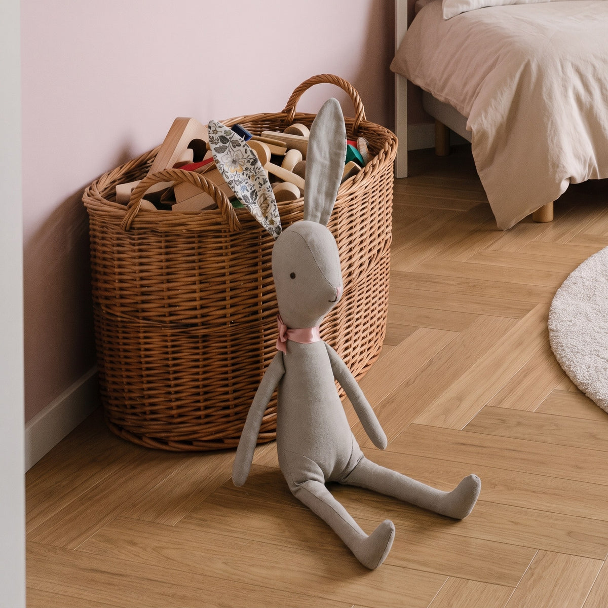 Doudou lapin gris adossé au panier de jouets en bois Image