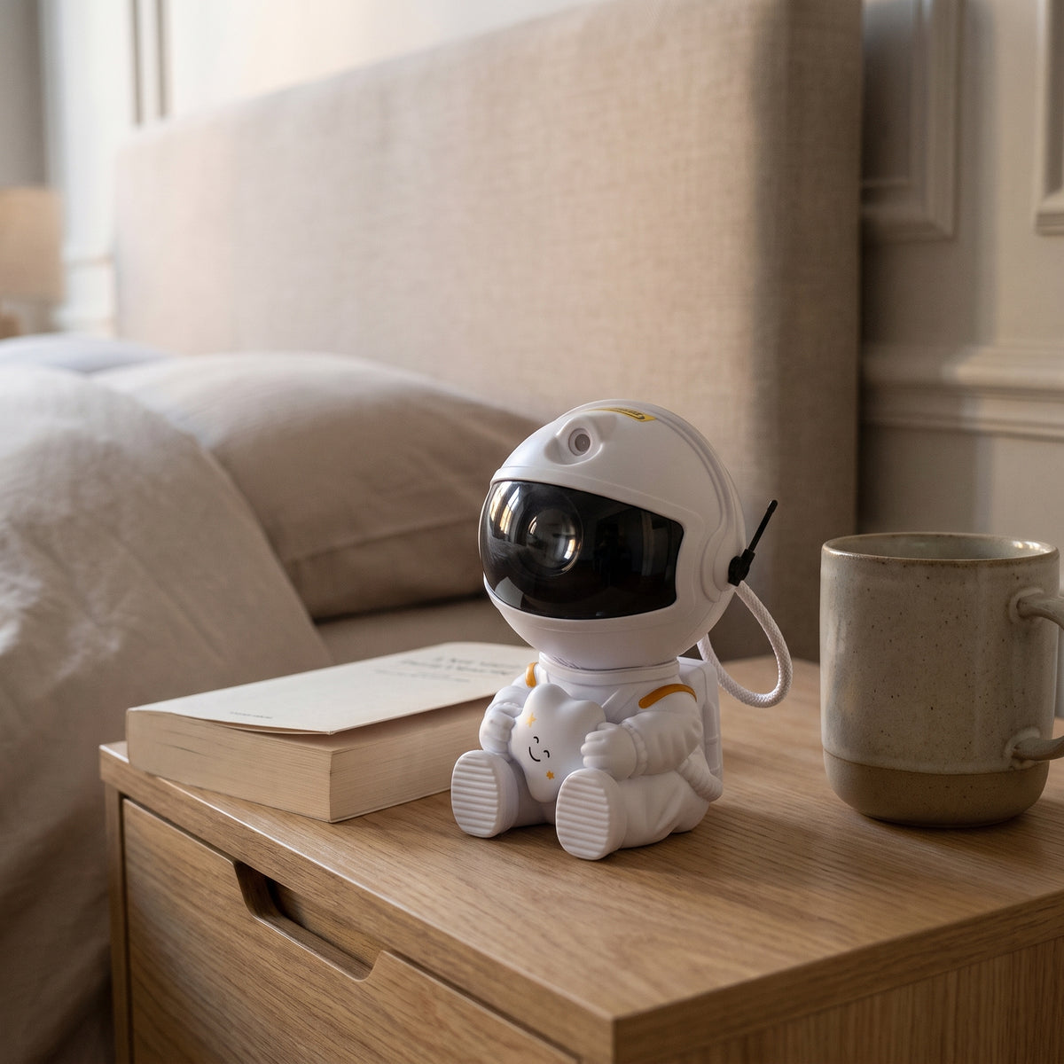 Veilleuse astronaute posée entre un livre et une tasse, qui donnent son échelle