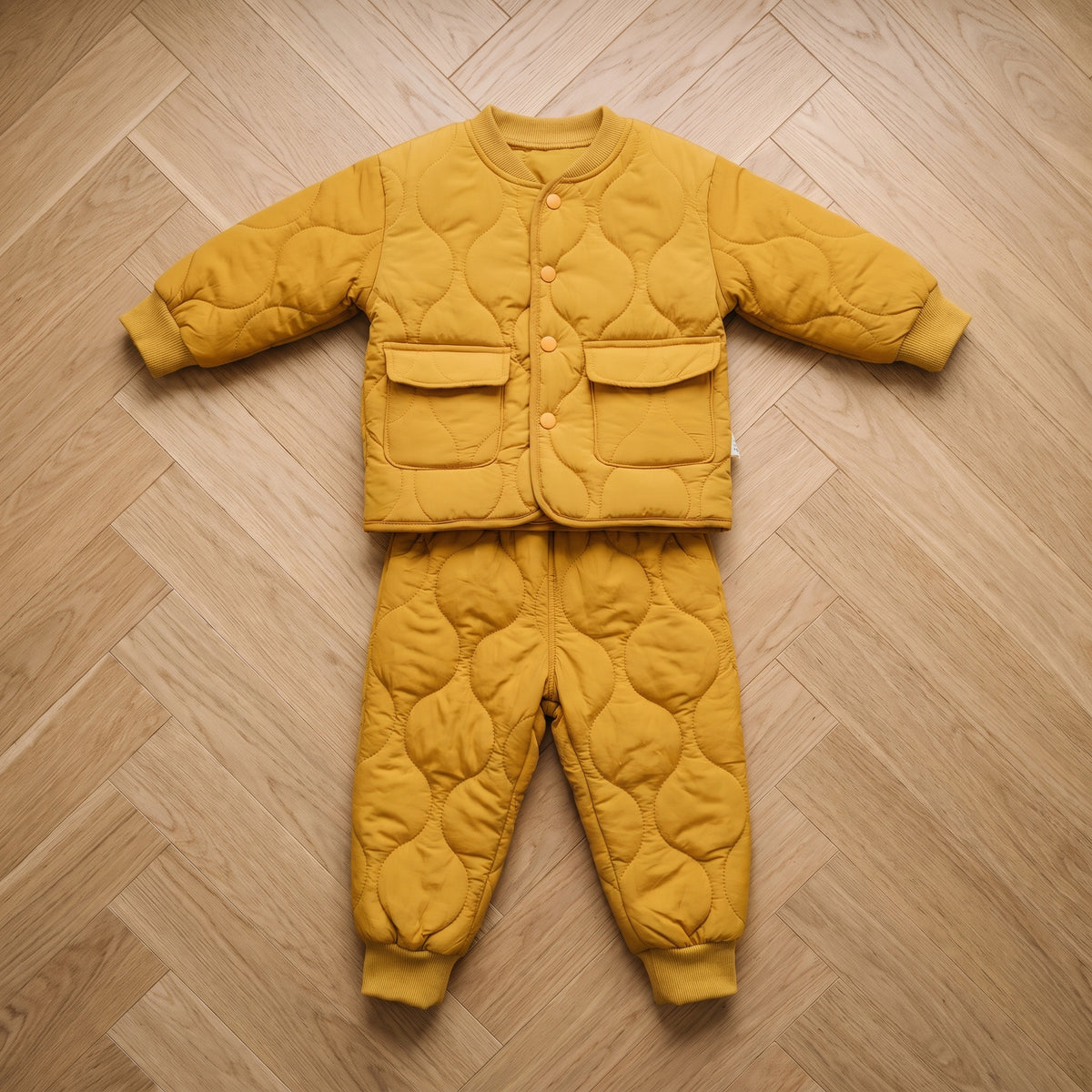 Ensemble bébé matelassé jaune moutarde, veste et pantalon posés à plat côte à côte Image