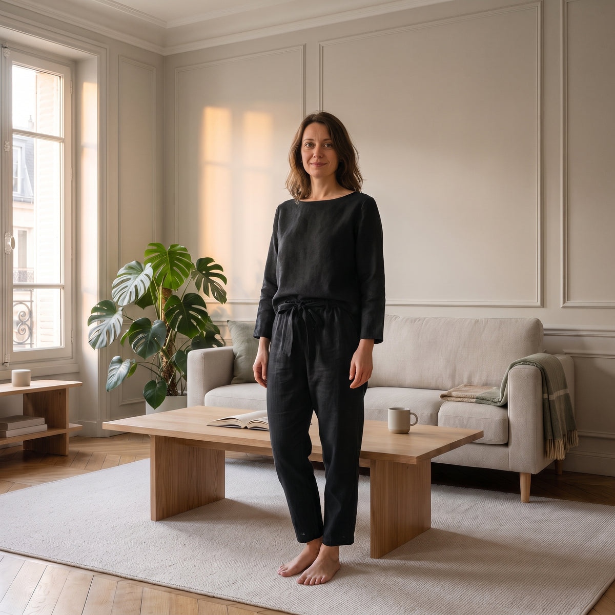 Ensemble en coton et lin noir porté, col bateau et pantalon à taille nouée, dans un salon clair