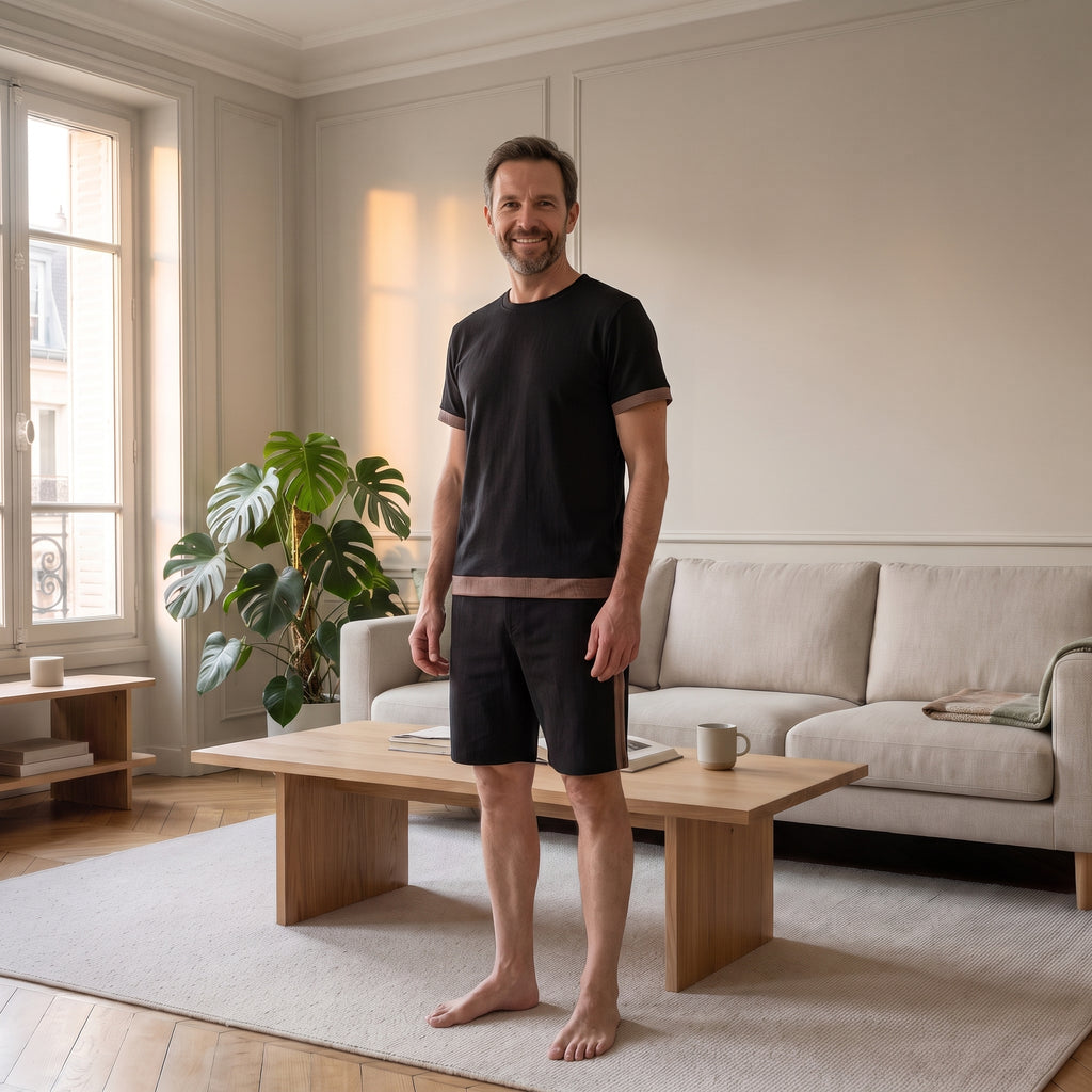 Homme portant l’ensemble short et tee-shirt noir dans un salon lumineux
