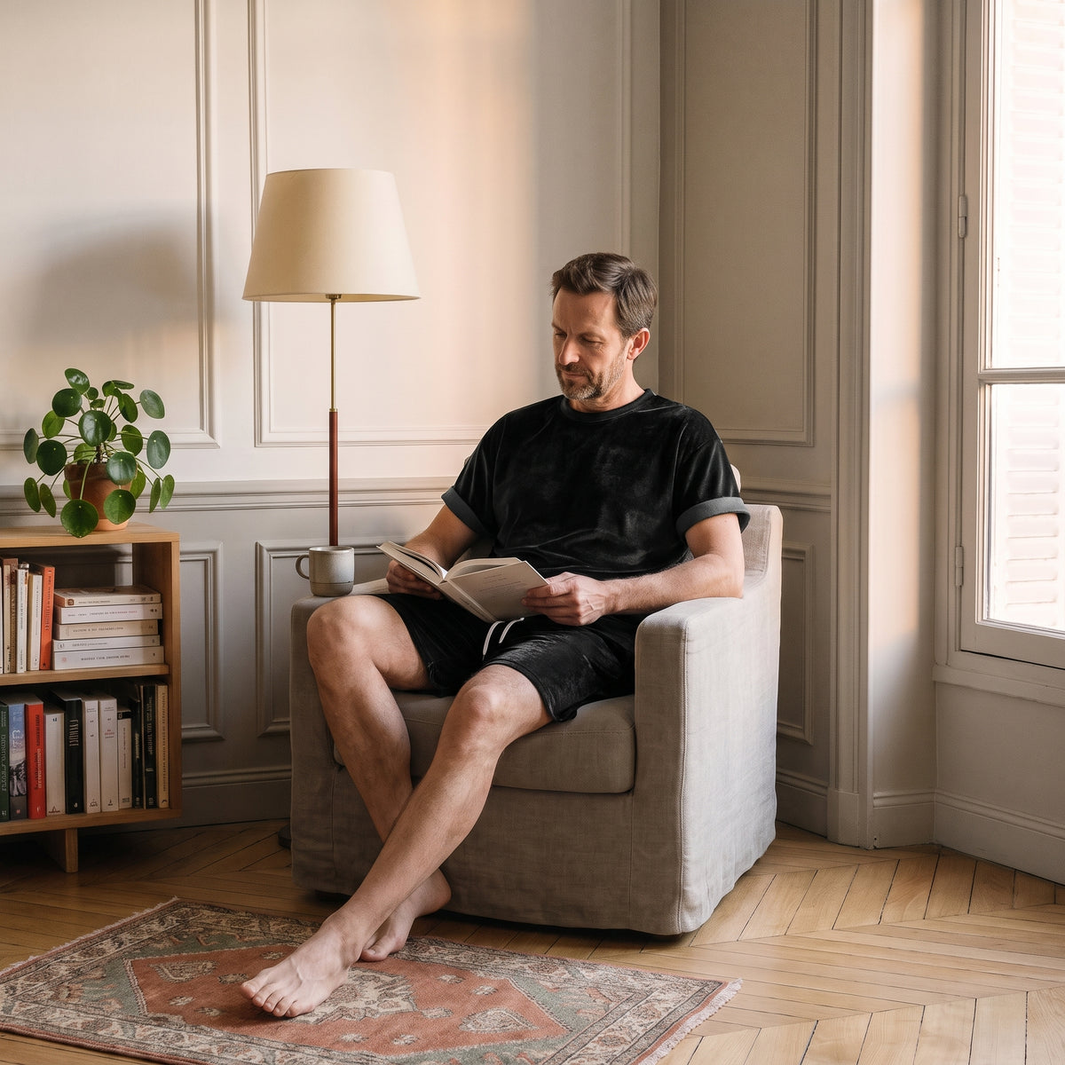 Homme du casting assis dans le fauteuil de lecture en ensemble de velours noir. Image