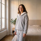 Femme portant le pyjama chaud gris à col châle écru dans une chambre lumineuse