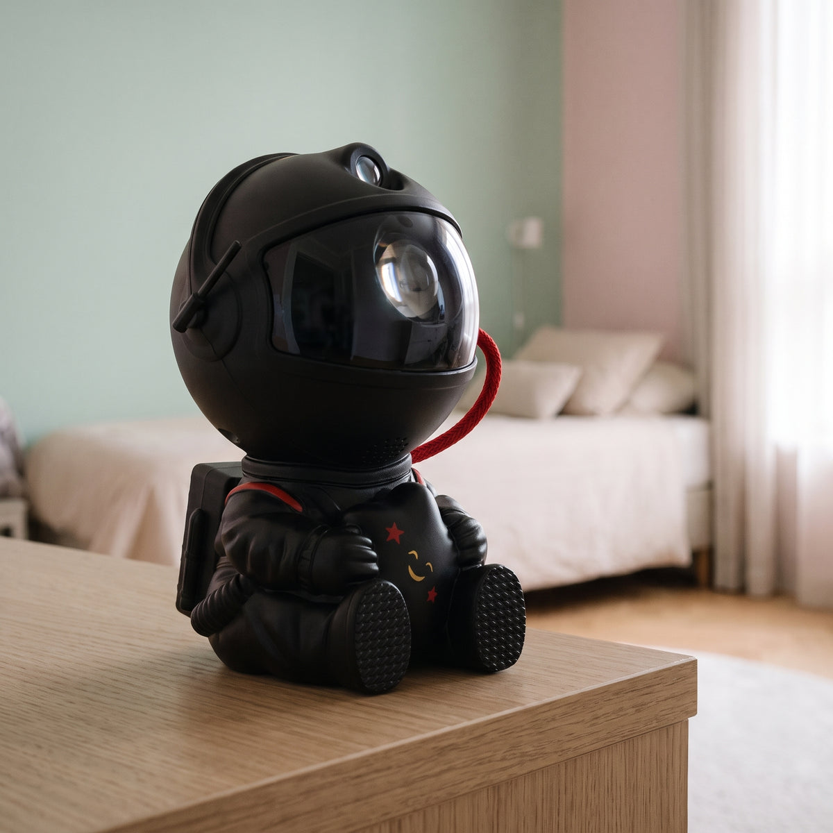 Veilleuse projecteur astronaute noir tenant une étoile, posée sur une table de chevet