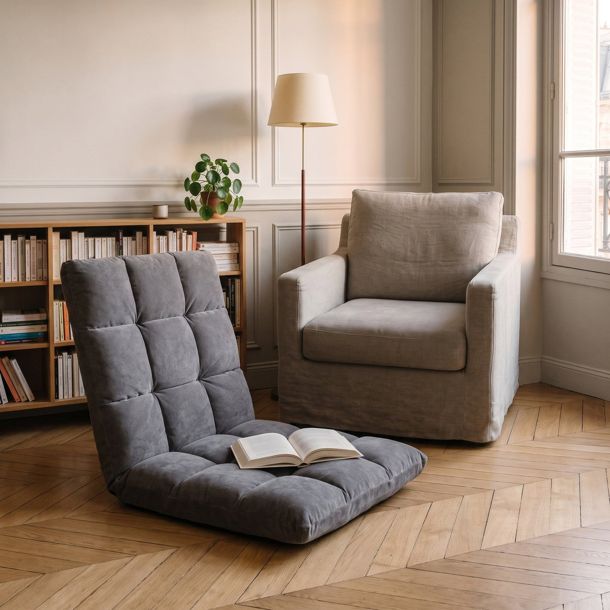 Fauteuil de sol gris installé devant une bibliothèque, un livre ouvert sur l'assise Image