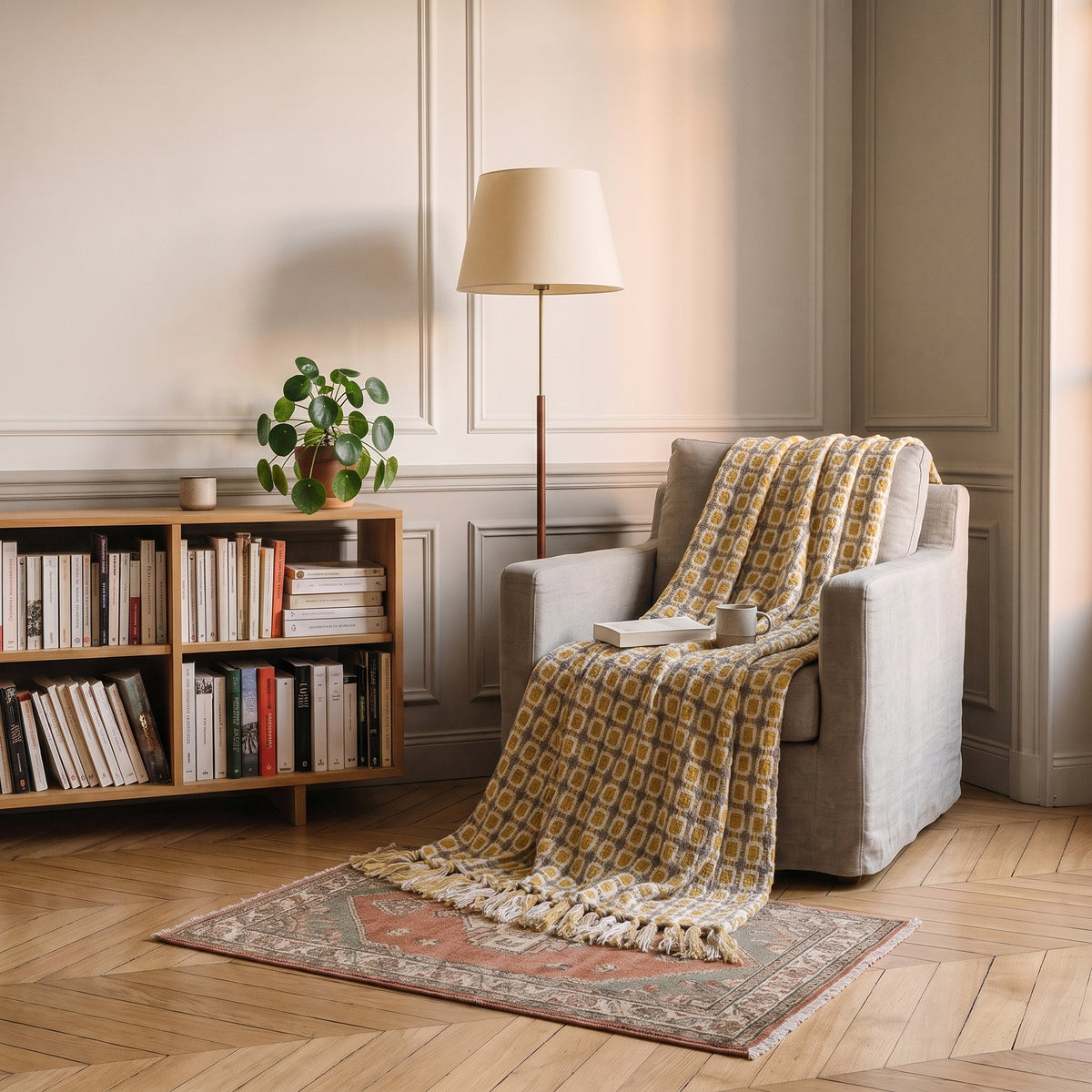 Plaid tricoté à losanges moutarde posé sur un fauteuil de lecture