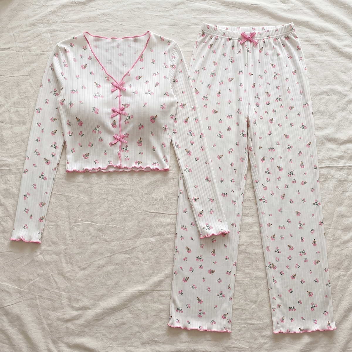 Haut à trois liens et pantalon à lien noué du pyjama floral blanc présentés à plat. Image