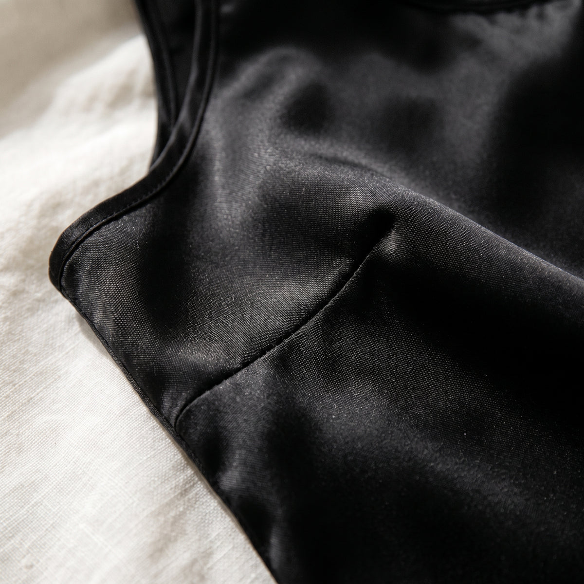 Gros plan sur le satin noir du débardeur, plis souples et couture d'assemblage Image