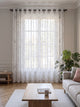 Voilage transparent blanc à motif feuillage, pans fermés devant la fenêtre d'un salon