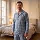 Homme en pyjama à carreaux en coton bleu clair, col uni et revers à carreaux, debout dans sa chambre