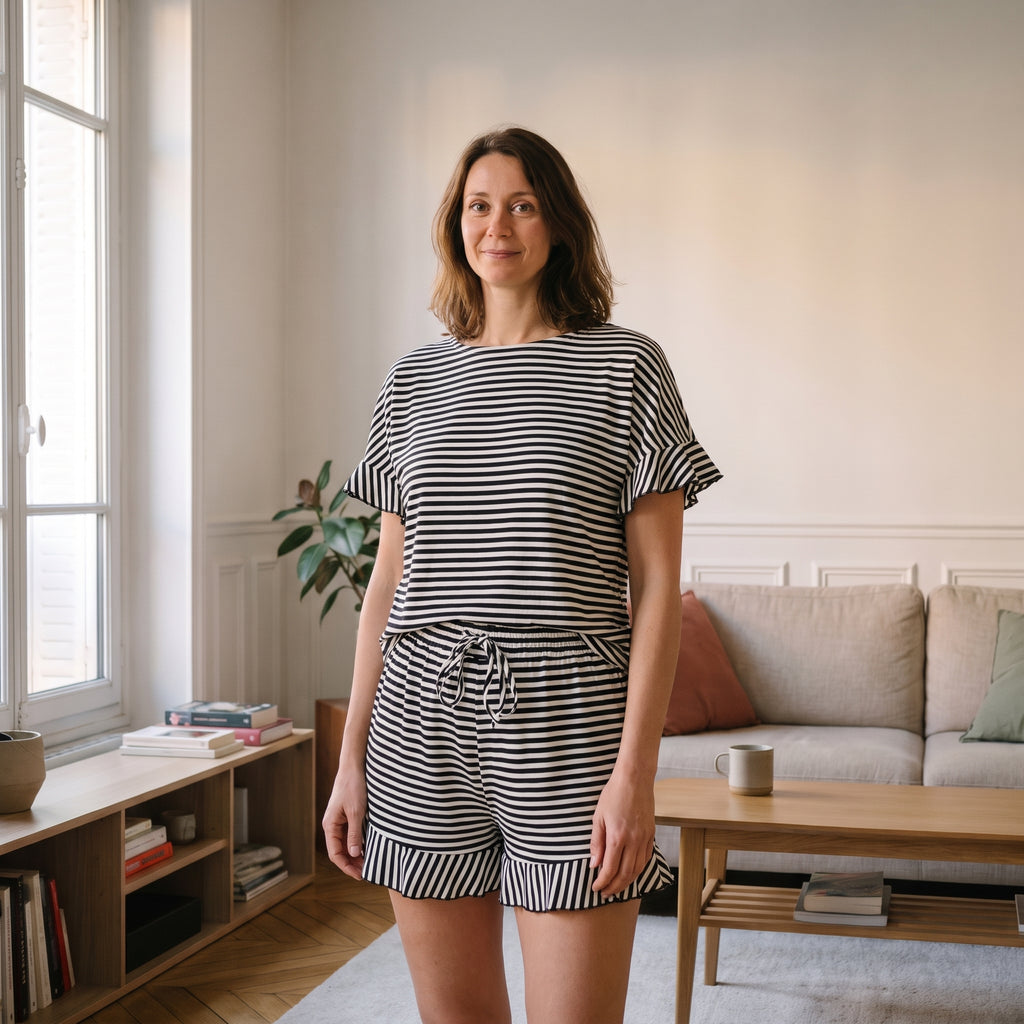 Ensemble pyjama d'été à rayures noires porté par une femme dans un salon