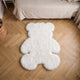 Tapis ourson en peluche blanc posé le long d'un lit d'enfant