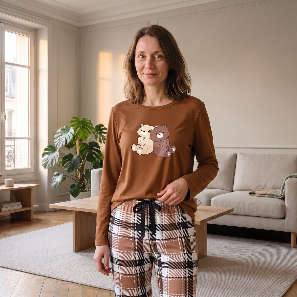 Femme debout dans son salon en pyjama marron a l imprime deux oursons et pantalon a carreaux