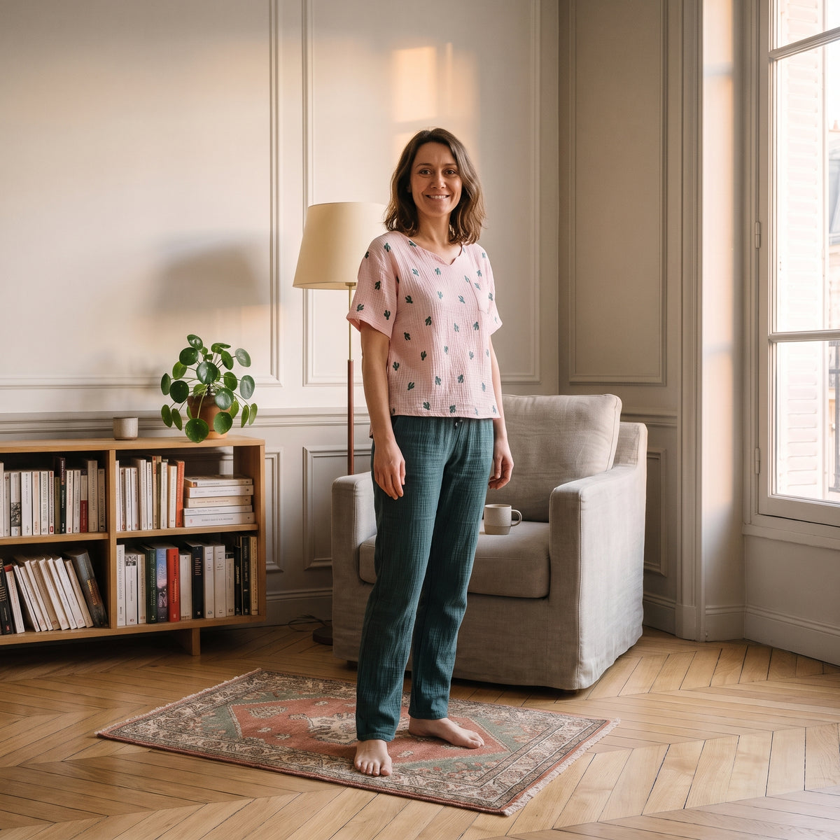 Femme en pyjama d'été rose en gaze de coton, debout dans son salon