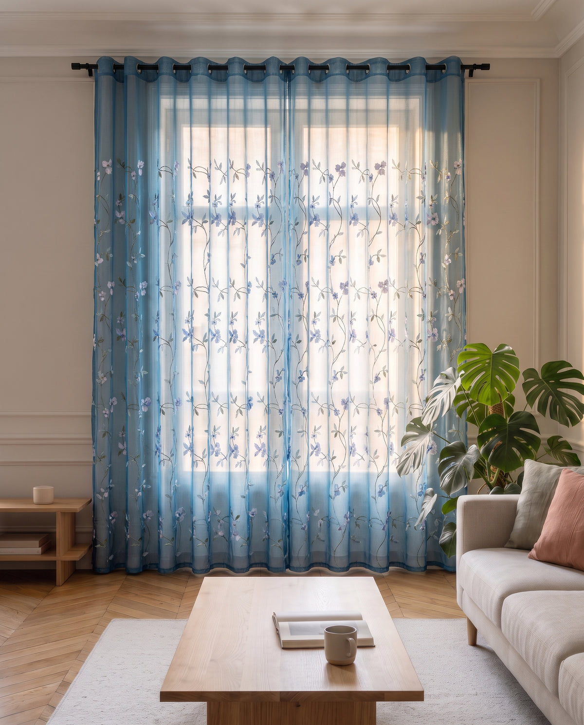 Voilage en tulle brodé bleu tiré devant la fenêtre d'un salon, du plafond jusqu'au parquet