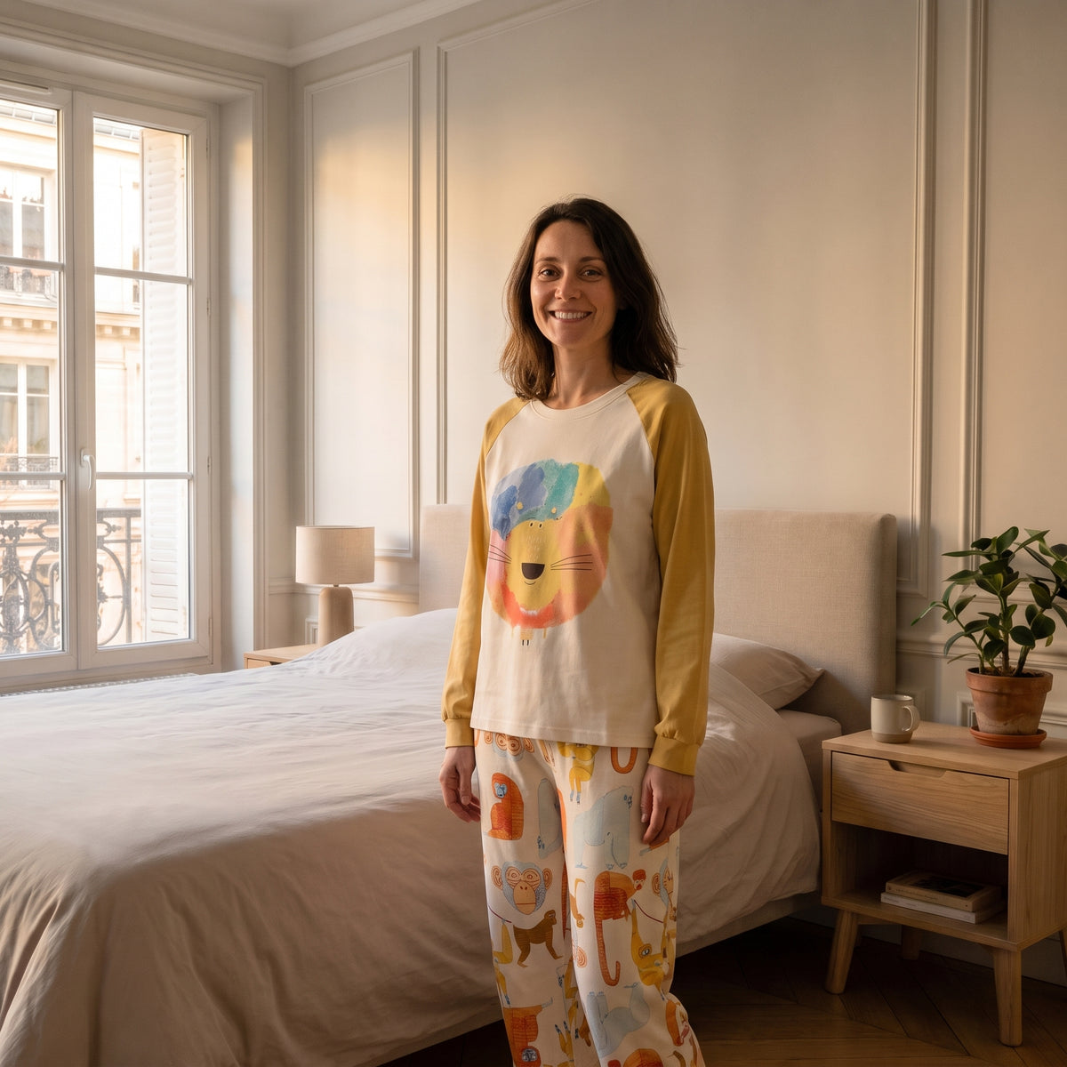 Femme debout en pyjama de coton écru, sweat-shirt imprimé lion et pantalon à motif singes