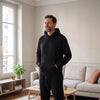Ensemble jogging homme en molleton noir, porté debout dans un salon