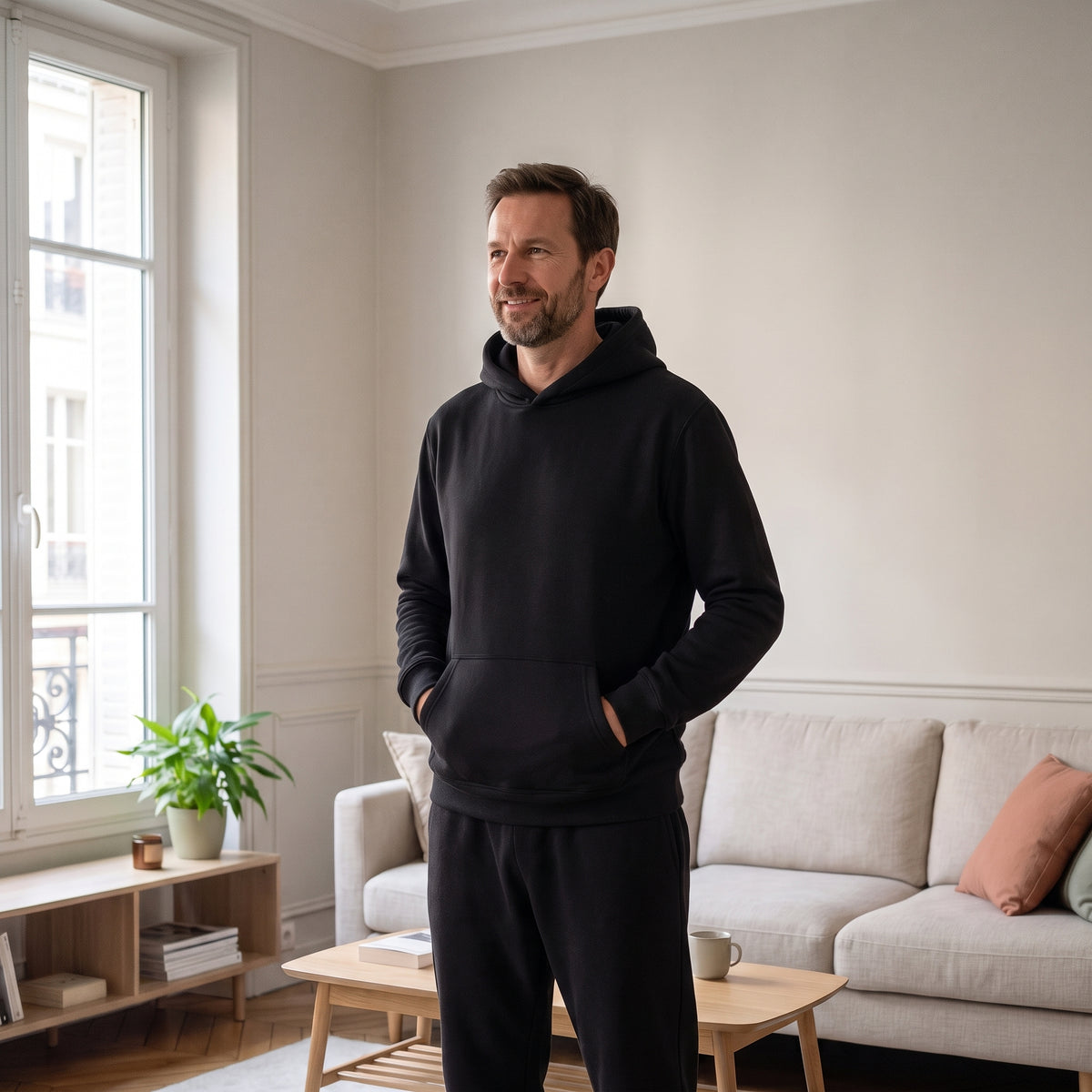 Ensemble jogging homme en molleton noir, porté debout dans un salon