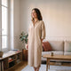Robe chemise longue beige sable portée debout dans un salon