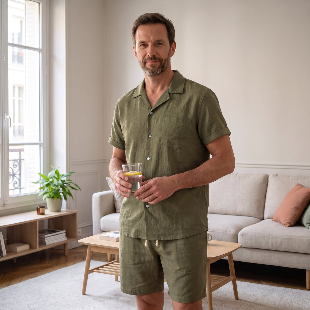 Homme debout sur une terrasse un matin d'été, en ensemble chemise et short kaki
