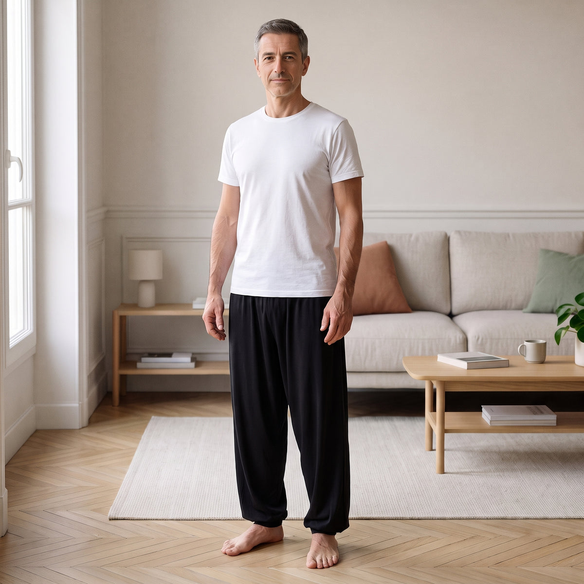 Homme debout dans une pièce claire en pantalon sarouel de yoga noir