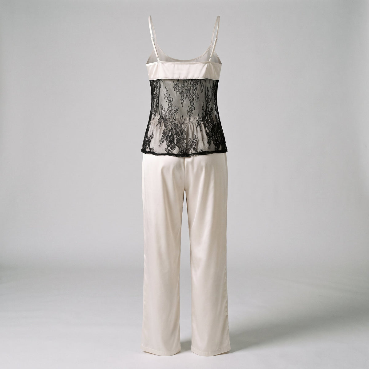 Ensemble de nuit en satin blanc casse sur mannequin invisible vu de dos, panneau de dentelle noire et pantalon long