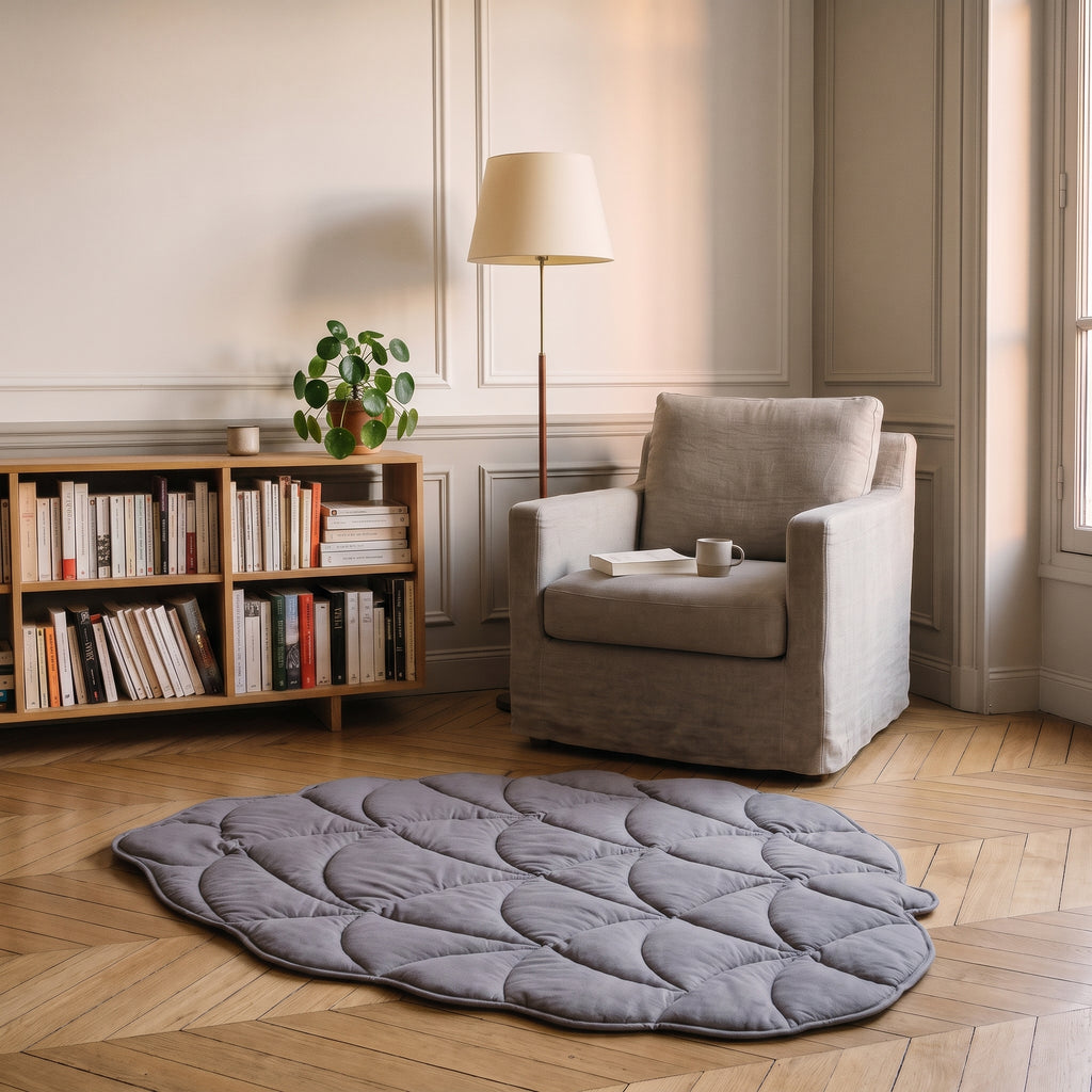 Tapis en forme de feuille gris parme au bord festonné devant un fauteuil