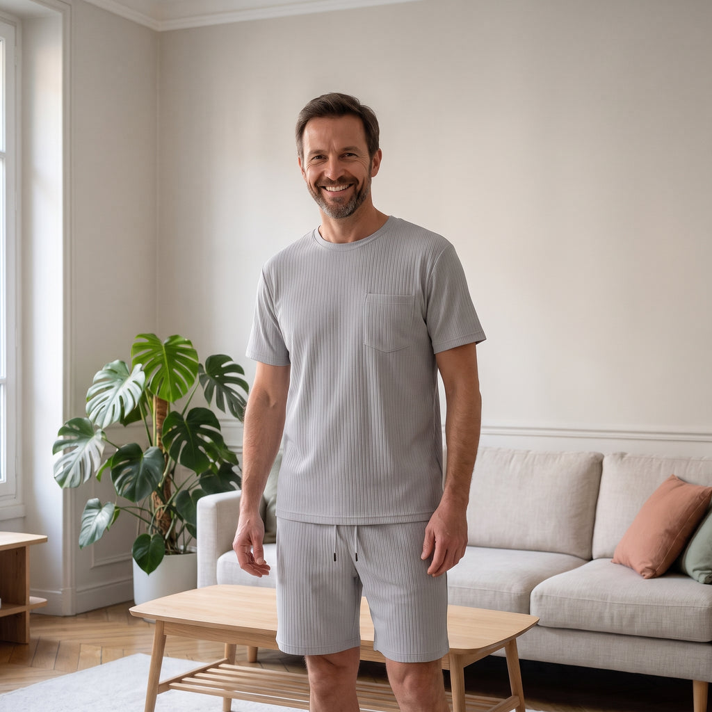Ensemble t-shirt et short gris en tissu plissé porté par un homme dans un salon