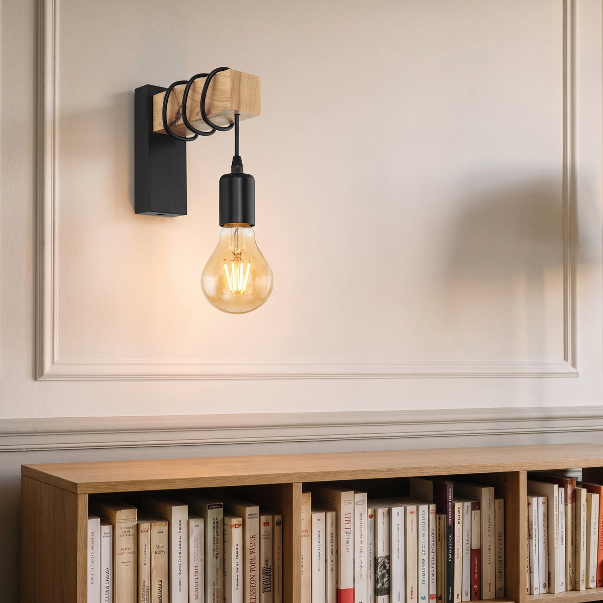 Applique murale en bois et métal noir allumée au-dessus d'une bibliothèque, ampoule à filament ambré