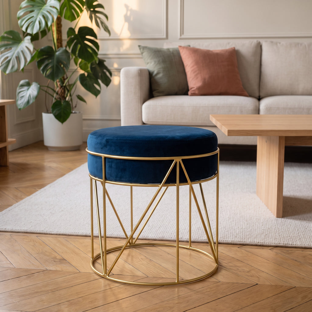 Pouf rond en velours bleu profond sur piètement doré, dans un salon clair