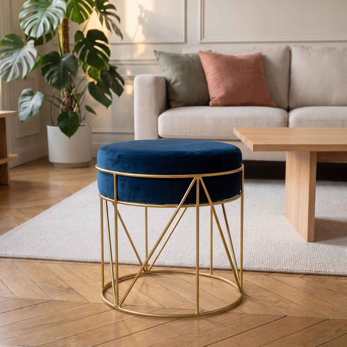 Pouf rond en velours bleu profond sur piètement doré, dans un salon clair