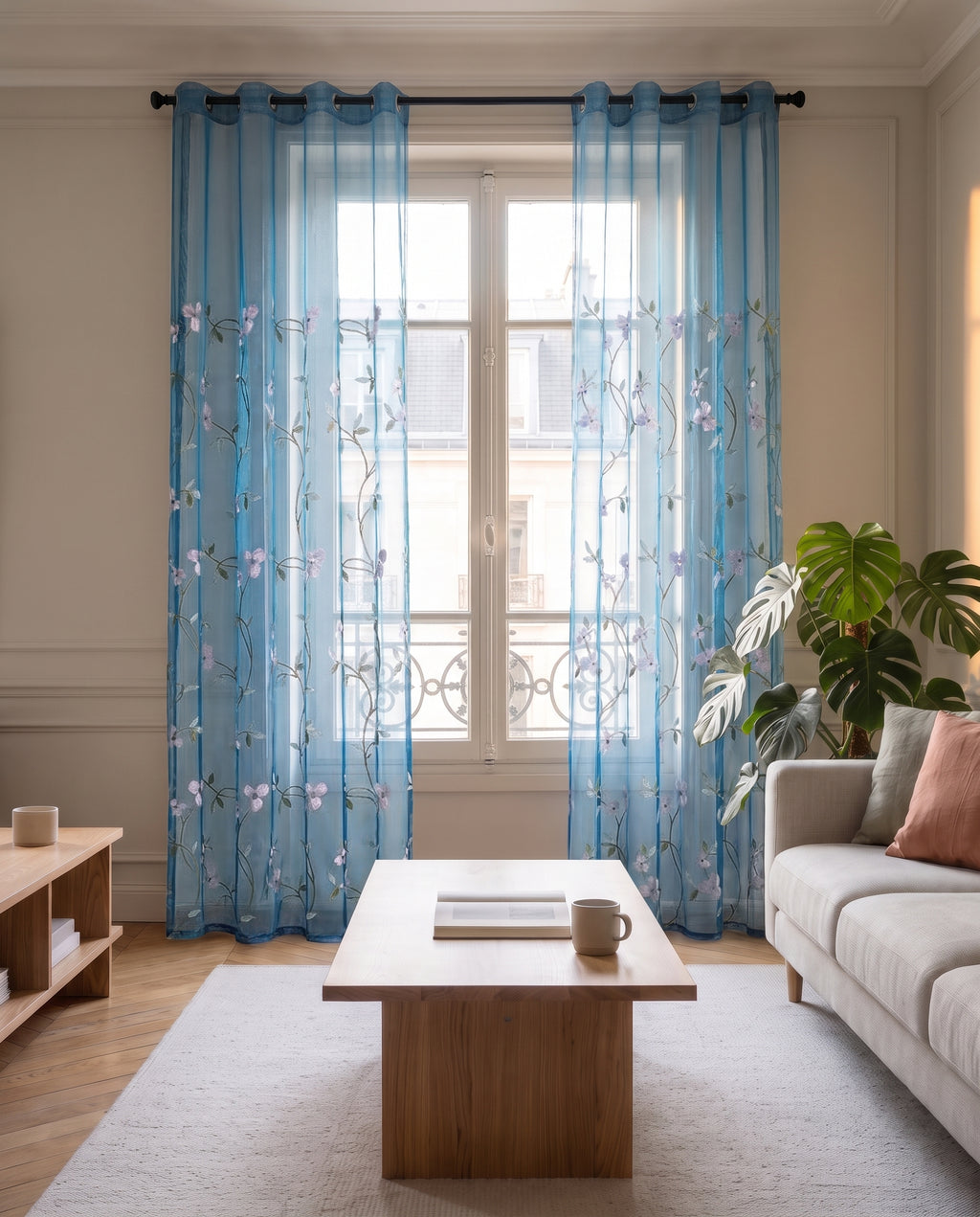 Voilage en tulle brodé bleu, les deux pans écartés de part et d'autre d'une fenêtre haussmannienne