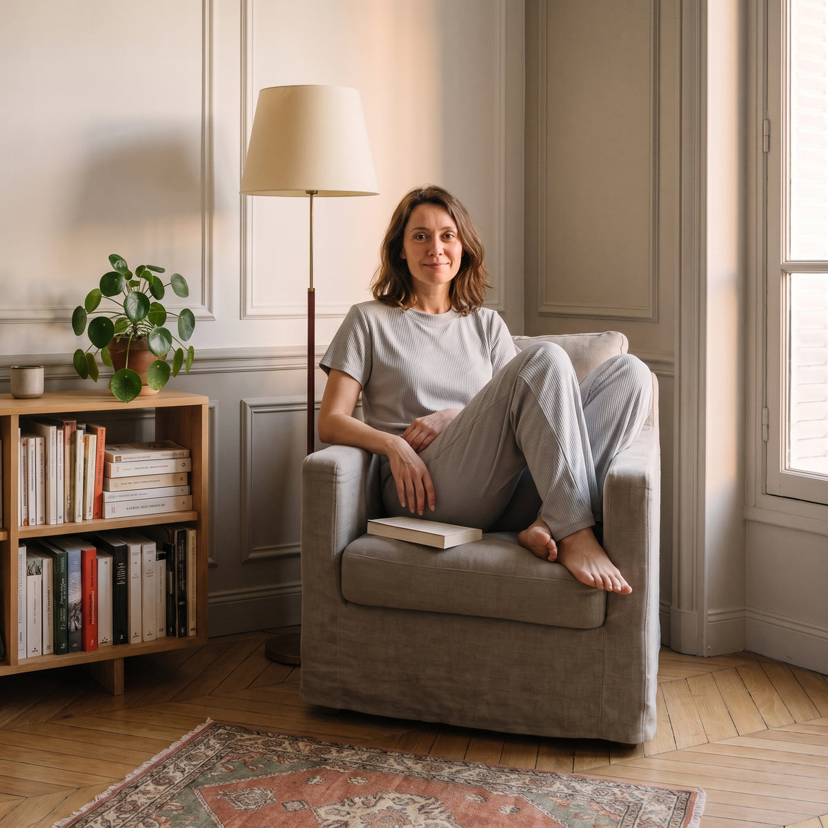 Pyjama femme côtelé gris perle porté assise dans un fauteuil de lecture, un livre sur les genoux