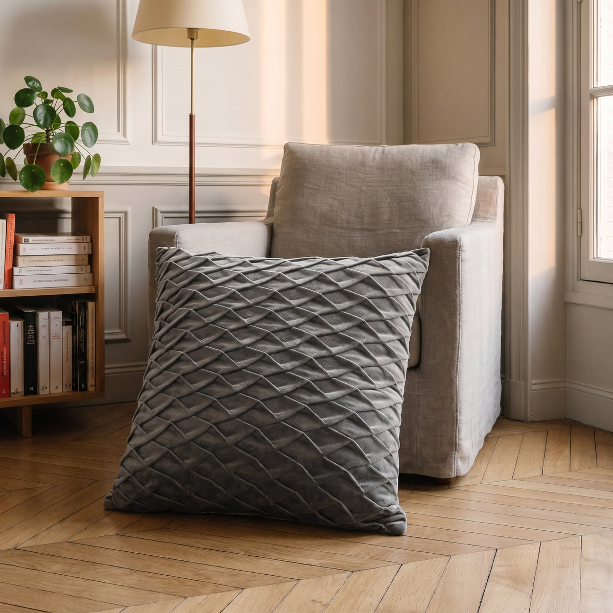 Housse de coussin en velours gris à écailles, posée dans un fauteuil de lecture
