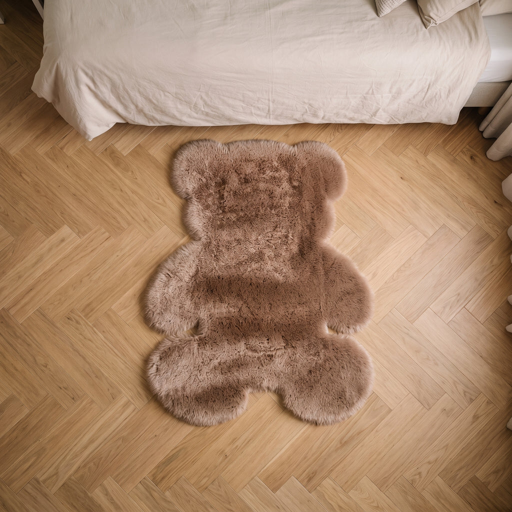Tapis ourson en peluche marron posé le long d'un lit d'enfant