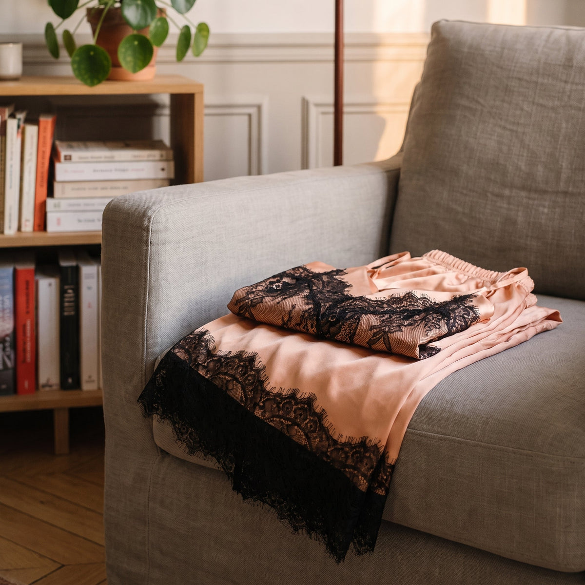 Ensemble en satin saumon plie sur le fauteuil du coin lecture, bord de dentelle noire retombant