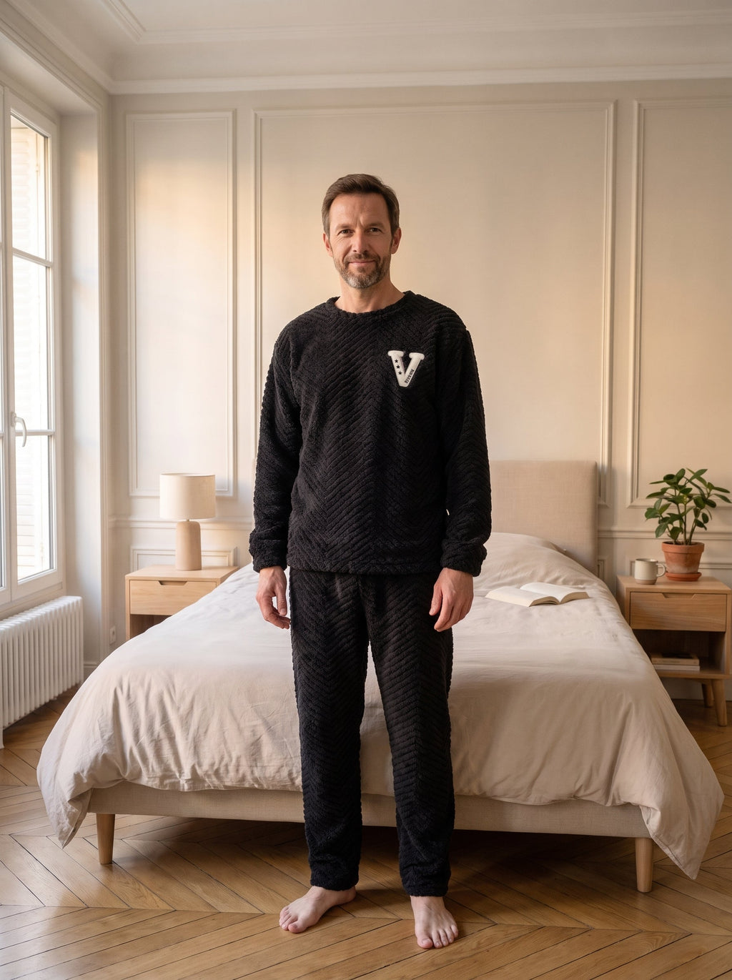 Pyjama polaire noir a chevrons porte debout dans la chambre, lettre V blanche appliquee sur la poitrine.