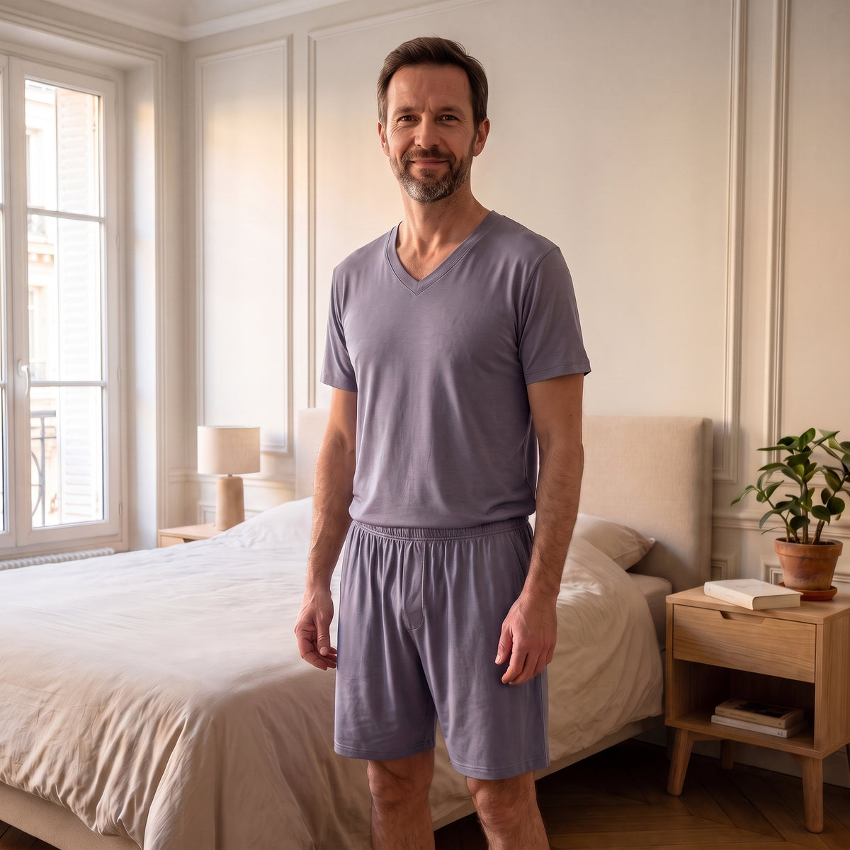 Homme en pyjama d'été en viscose violet grisé, t-shirt col V et short, debout dans la chambre