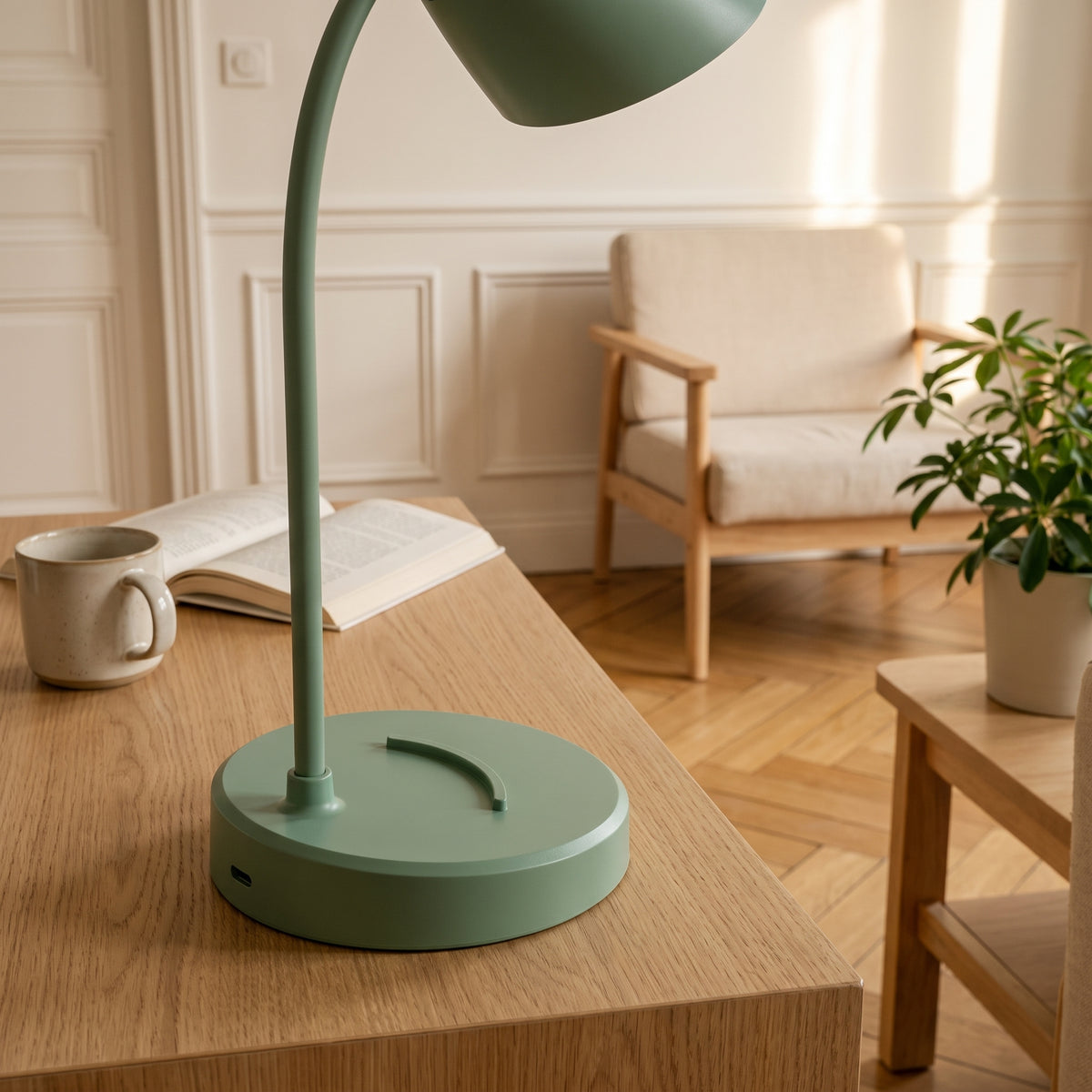 Gros plan sur le socle vert de la lampe : l'arc creusé dans le plateau, le pied du bras, et l'ouverture de recharge ménagée dans la tranche.
