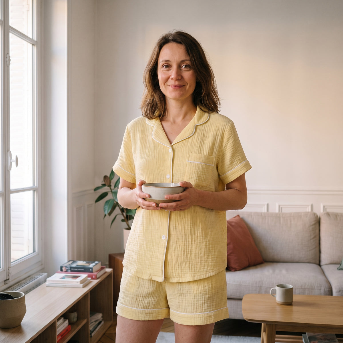 Pyjama d'été en gaze de coton jaune pâle, porté debout près de la fenêtre