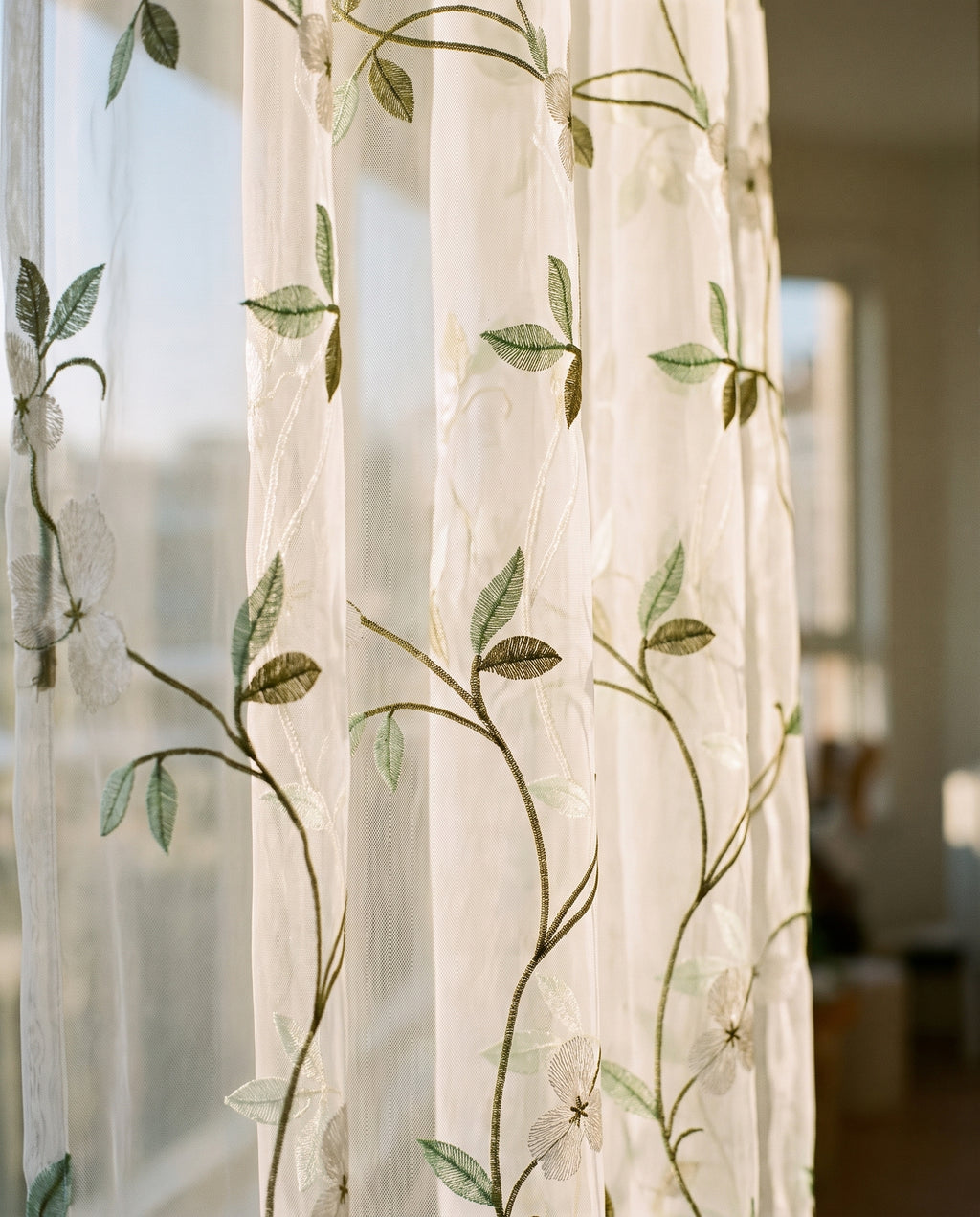 Détail de la broderie verte sur le tulle blanc, vue à contre-jour