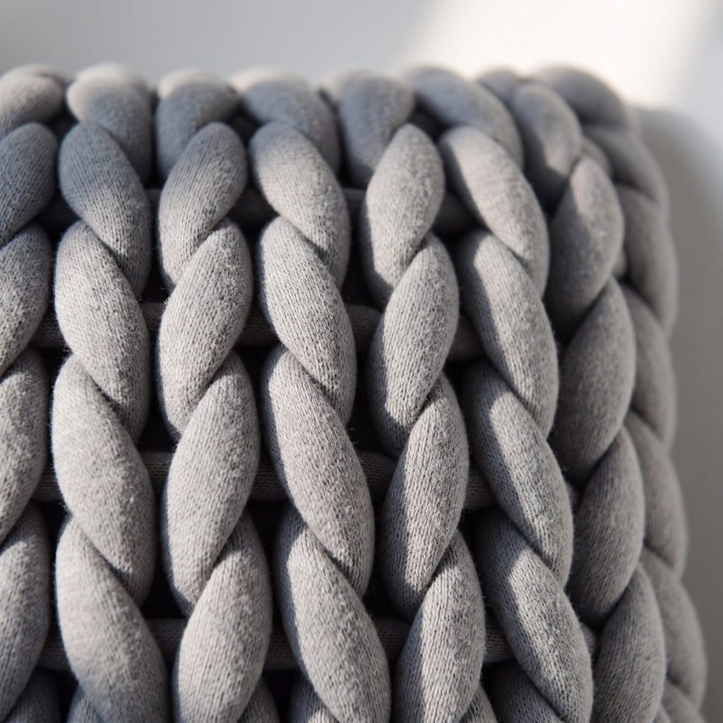 Détail du tricot du coussin, cordon tubulaire roulé en maille géante