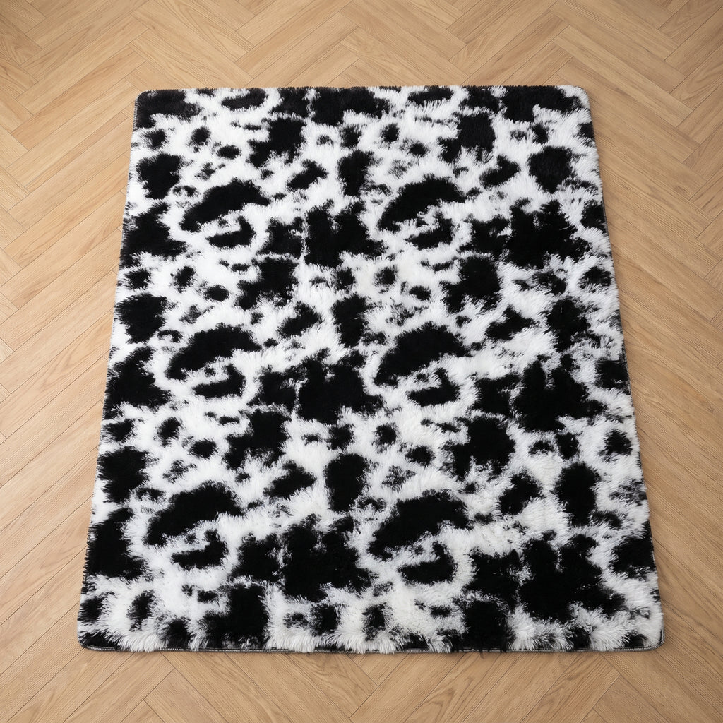 Tapis vache à poils longs vu en entier, posé à plat sur un parquet clair