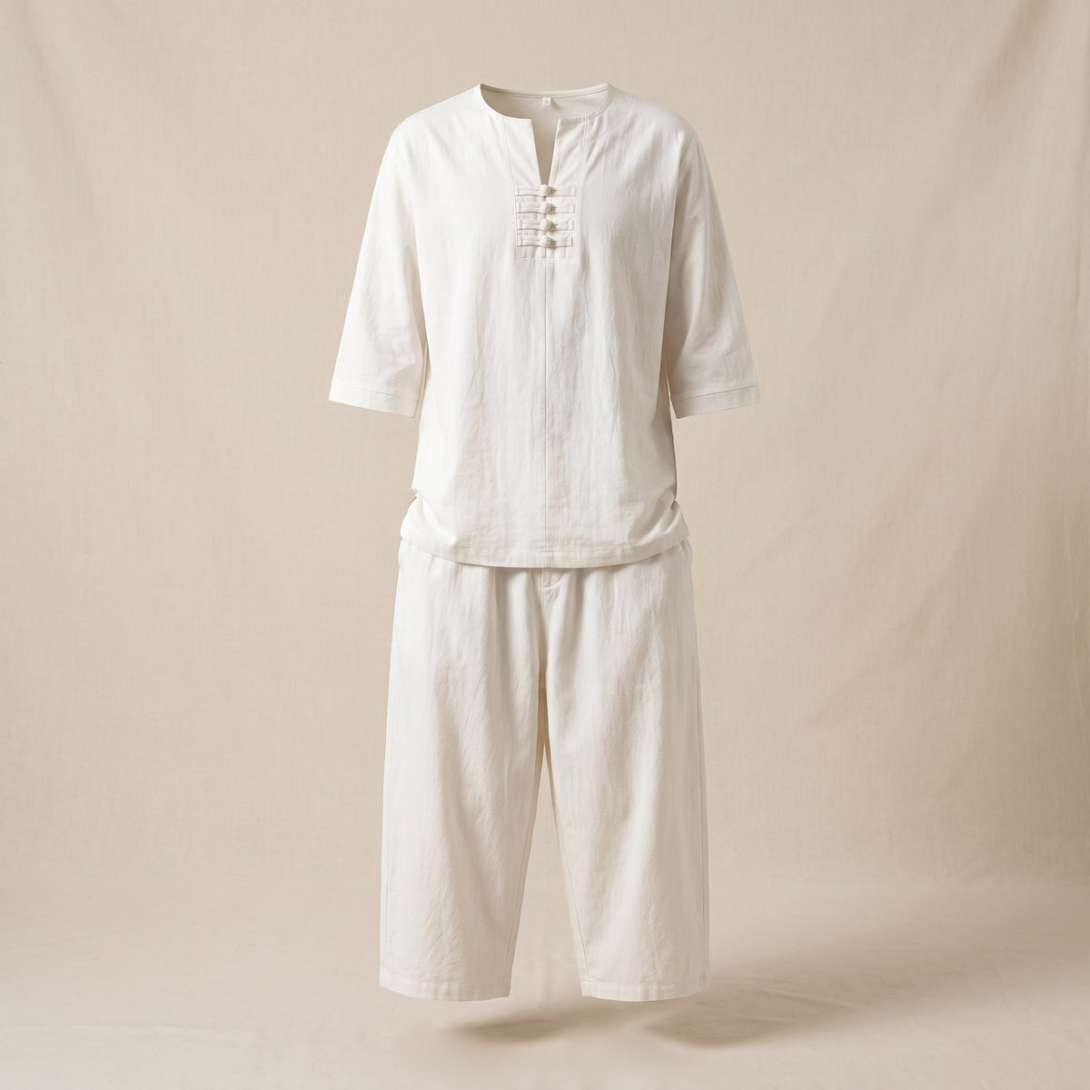 Haut et pantalon blancs de l'ensemble présentés sans mannequin sur fond clair